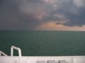 Thunder clouds gather over the ocean as seen from the deck of a ship