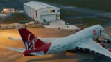 A modified Boeing 747-400 in front of an aircraft hangar labelled Spaceport Cornwall