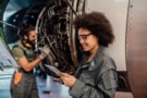 Man and woman working on an aeroplane engine