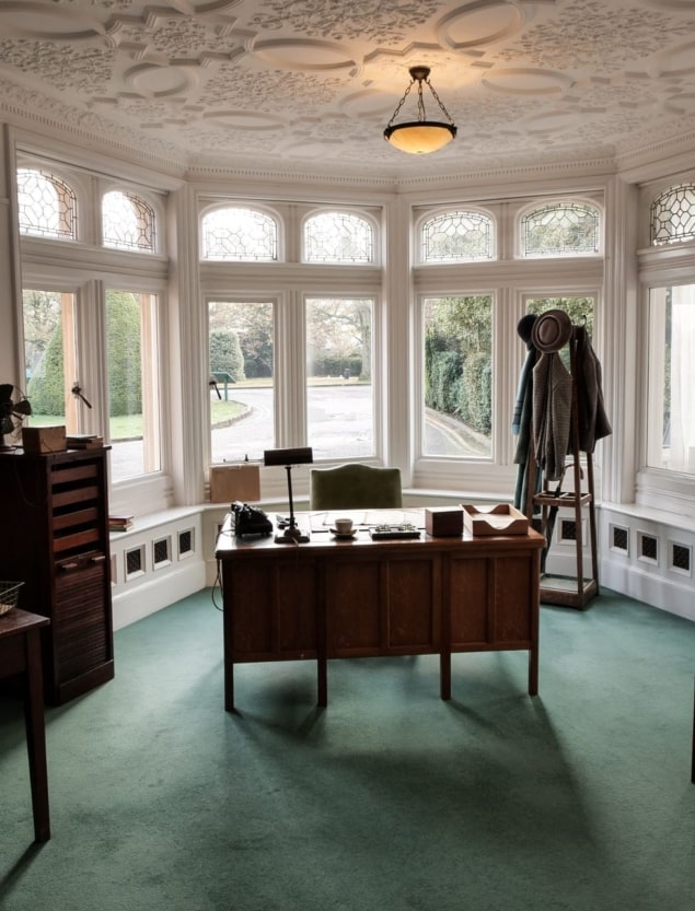 Alastair Denniston's office at Bletchley Park, containing an old-fashioned wooden desk, chair, lamp, and coat rack