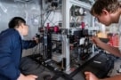 Two people make adjustments to an experimental apparatus on an optical bench