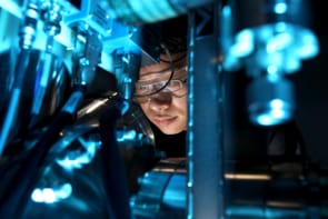 Photo of a person using a microscope, bathed in blue light