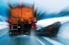 Photograph of a a winter maintenance truck spreading salt and clearing snow on a road in Norway