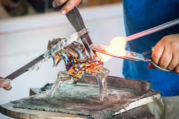 a glass blower creates a glass horse