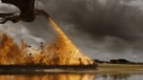 A still from Game of Thrones showing a dragon flying and breathing fire