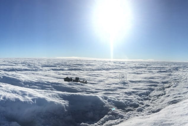 Photo of instruments sitting on an ice sheet with the Sun bright in a blue sky above