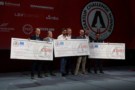 A group of people standing holding giant cheques