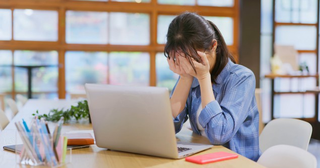 Person sat at a desk with their head in their hands