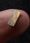 A photonic chip balances on a person's finger