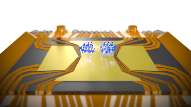 Artist’s depiction of two spatially separated entangled rubidium atom clouds on top of a micro-fabricated gold atom chip. The atom clouds are shown as blue dots and sit in the middle of gold wiring on the chip